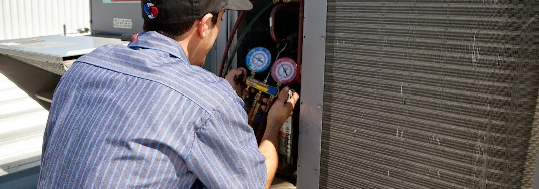 HVAC technician servicing a condenser unit in Simsbury